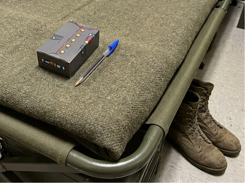 Old Guard Soap Co, soap box lying on a military bed and pen on a military-style cot with boots in the background